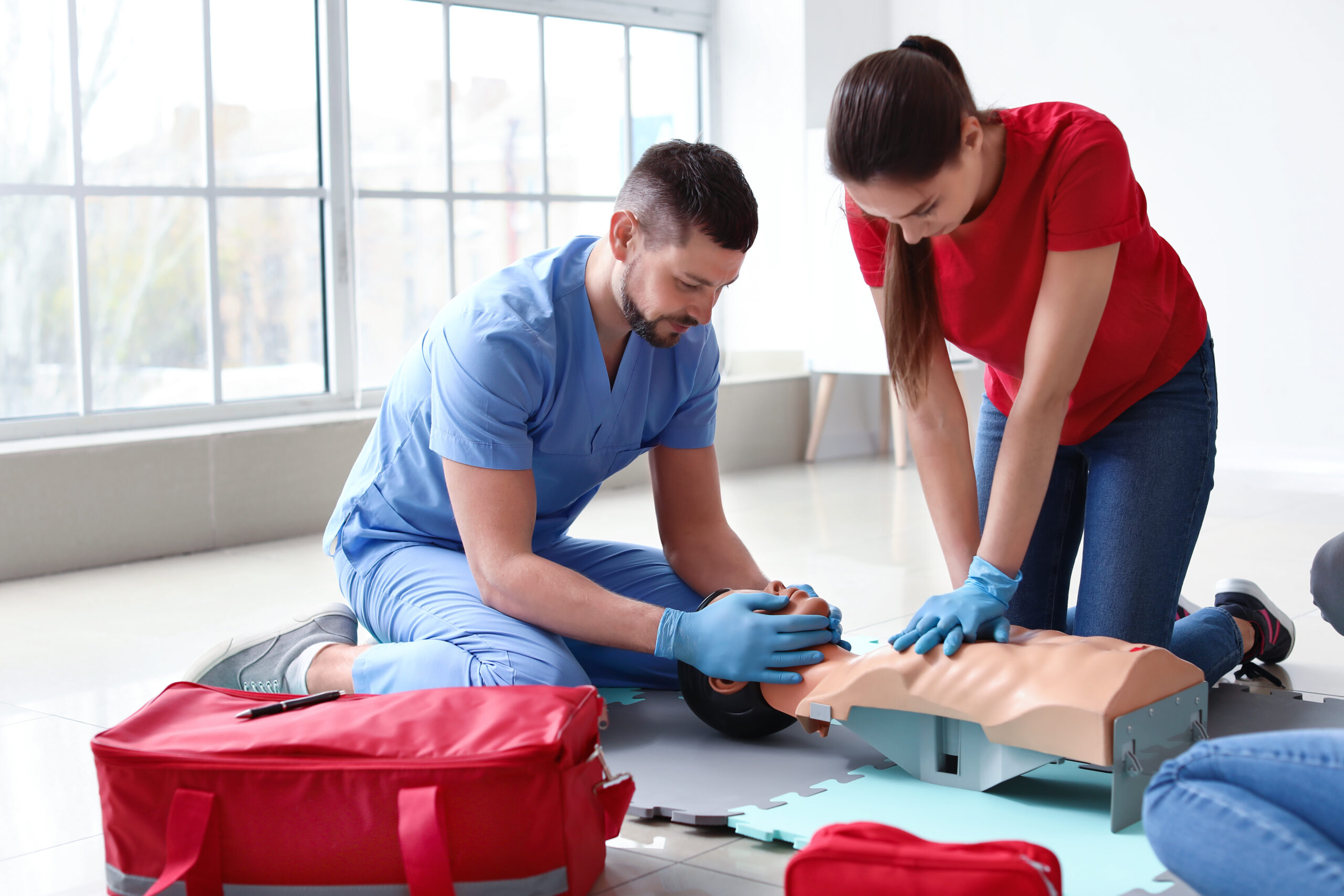 Instructors demonstrating CPR on mannequin at first aid training course